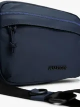 Bandolera Tommy Hilfiger azul marino con correa ajustable de tejido trenzado, cierre de cremallera, bolsillo exterior con cremallera y logo texturizado en la parte delantera.