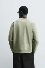 Sudadera verde militar de algodón con interior de rizo, corte relaxed fit, cuello redondo y mangas largas con puños y ruedo acanalados.