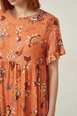 Vestido corto color naranja con estampado floral multicolor, de corte holgado y mangas cortas con volados.