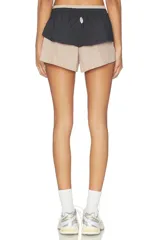 Short deportivo de nylon color beige con una capa superior negra fruncida en la cintura, con cordón blanco ajustable.