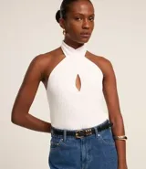 Blusa blanca de punto canelado con escote halter cruzado y abertura en el busto.
