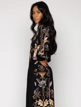 Pantalón de viscosa negro con estampado floral en tonos dorados, marrones y grises.