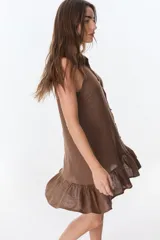 Vestido corto color ladrillo, sin mangas, con cuello camisero con volados, abotonado al frente y falda con volados.