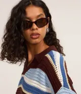 Remera oversized de punto con rayas horizontales en tonos marrón, celeste y blanco. Presenta cuello polo y mangas cortas.