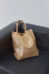 Bolso tipo shopper grande color dorado con textura brillante.