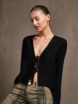 Blusa negra con estampado animal print en blanco y marrón, escote en V con lazo ajustable y mangas largas acampanadas.