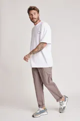 Pantalón de vestir color beige, de corte recto, con bolsillos laterales y traseros. Se ajusta a la cintura con cinturón de cuero marrón.