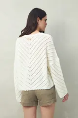 Sweater negro calado con diseño de líneas diagonales en relieve y mangas acampanadas.