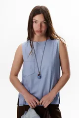 Top sin mangas color terracota con cuello redondo y bolsillo frontal. Presenta costuras a contratono en blanco que definen los bordes y el bolsillo.