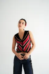 Chaleco calado negro con diseño de rayas diagonales rojas, beige y blancas.