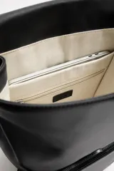 Mochila negra de cuero sintético, con solapa y cierre magnético. Tiene un compartimento principal con espacio para dispositivos electrónicos de hasta 13 pulgadas y un bolsillo con cierre. En la parte frontal cuenta con un bolsillo con cierre. Tiene asa de mano y dos asas de hombro ajustables y acolchadas.