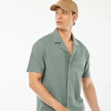 Camisa verde de manga corta con cuello de remera y cierre con botones.