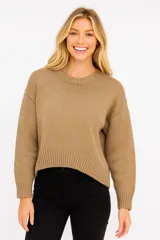 Sweater de punto color beige oscuro, con cuello redondo y mangas largas. Diseño holgado y tejido acanalado.