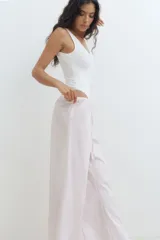 Pantalón de pijama de corte holgado en algodón a rayas verticales color lila y blanco. Modelo de tiro bajo con elástico revestido en la cintura y cordón para ajustar.