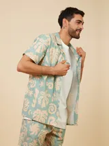 Camisa manga corta celeste con estampado de hojas color beige, cuello clásico y calce regular.