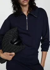 Sweater beige de cuello alto con cierre de cremallera, diseño oversize y mangas largas.