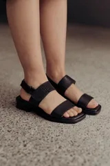 Sandalias bajas doradas de cuero, con punta cuadrada, tiras anchas y cierre con hebilla ajustable.