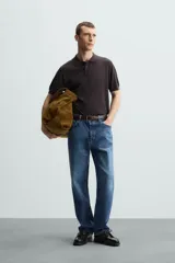 Polo negro de punto tejido en hilatura con algodón y lyocell, corte regular fit, cuello solapa con cierre frontal de botonadura, manga corta y acabados en rib.