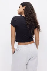 Remera negra entallada de punto elástico, corte crop y cuello redondo.