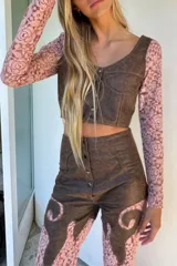 Pantalón de cuero negro con aplicaciones de encaje floral, tiro alto y corte oxford.