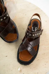 Sandalias negras de charol con tiras cruzadas y plataforma track.