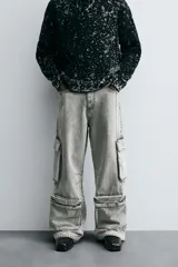 Pantalón relaxed fit de denim negro con efecto lavado, bolsillos frontales, traseros de plastrón y multifunción en perneras. Bajo ajustable con trabilla y cierre frontal con cremallera y botón.
