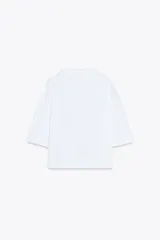 Camiseta blanca de algodón, corte oversize, cuello redondo, manga corta y detalle de aplique metálico con logo ZA en el frente.