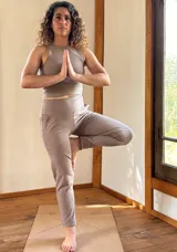 Conjunto deportivo de dos piezas en color verde oscuro, compuesto por un top reversible con escote redondo y un pantalón slim de tiro alto con faja ancha y bolsillos.