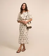 Blusa de hombros descubiertos color crema con estampado floral azul, mangas cortas abullonadas y detalle de hilo metalizado.