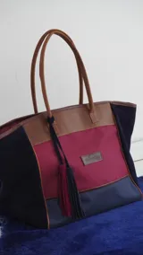 Bolso de fin de semana tipo tote bag, confeccionado en lona y gamuza, con detalles en cuero color marrón. Tiene un bolsillo interno con cierre.