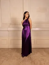 Vestido largo de fiesta color violeta metalizado, con textura plisada y diseño de un solo hombro.