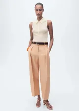 Pantalón color piel, de corte recto y largo cropped, con pinzas en la cintura, cierre frontal oculto, trabillas y bolsillos laterales.