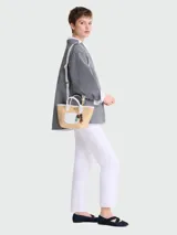 Bolso bandolera Longchamp Le Panier Pliage XS, confeccionado en rafia color beige con detalles en cuero blanco y herrajes dorados.