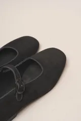 Zapato estilo Mary Jane color marrón, de cuero, con punta redondeada y tira sobre el empeine con hebilla.