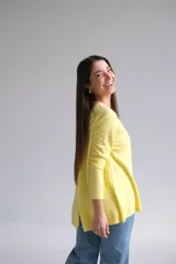 Sweater amarillo de corte recto con cuello redondo. La parte delantera es más corta que la trasera y tiene aberturas en la espalda.