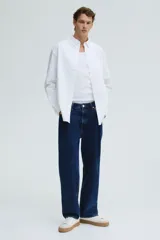 Camisa blanca de algodón Oxford con cuello americano, tapeta clásica, bolsillo superior abierto y canesú en la espalda. Mangas largas con puños abotonados y bajo levemente redondeado. Corte estándar.
