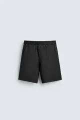 Bermuda negra de corte relajado, confeccionada en tejido satinado de viscosa. Presenta cintura elástica ajustable con cordón interior, bolsillos frontales y un bolsillo trasero de plastrón.