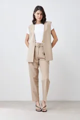 Pantalón de vestir color beige, de corte recto, con pinzas, bolsillos laterales y cinturón con hebilla forrada.
