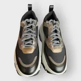 Zapatillas deportivas color beige con cordones a rayas en blanco y negro, suela de goma con plataforma y diseño chunky.