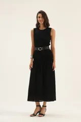 Vestido midi negro de lino, sin mangas, con escote redondo y falda fruncida. Incluye cinturón de cuero trenzado con hebilla metálica.