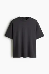 Remera negra de algodón pesado, corte holgado, con cuello redondo ribeteado, hombros caídos y bajo recto.
