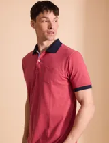 Remera polo blanca de piqué con cuello y puños en azul marino. Tiene tapeta de dos botones y bolsillo de parche en el pecho.