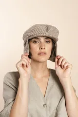 Boina con visera y orejeras, con estampado a cuadros en tonos beige y blanco.