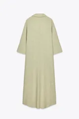 Vestido camisero blanco confeccionado en lino, de corte recto y largo midi. Presenta cuello camisero, mangas 3/4 con puños abotonados, cierre frontal con botones y abertura en el ruedo.