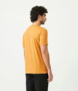 Remera color mostaza de corte slim fit, cuello redondo y manga corta. Presenta un estampado tipográfico en el pecho.