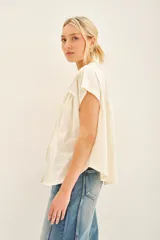 Camisa negra de manga corta con combinación de tejido de punto y plano, detalles de volados y frunces en pechera y espalda, acceso con botones fake nacar y medallita marcaria en espalda.