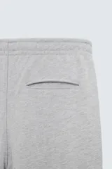 Pantalón jogger gris de corte recto, confeccionado en tejido de algodón compacto con interior en rizo. Tiene cintura elástica ajustable con cordón interior, bolsillos frontales y bolsillo de doble vivo en la espalda.