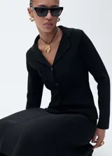 Chaqueta negra de punto con cuello de solapa, cierre frontal con botones, diseño entallado y manga larga.