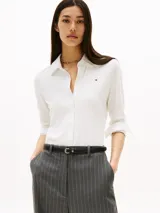 Camisa blanca de piqué de algodón elástico, corte slim, con cuello camisero, cierre de botones, puños con botón y logo de Tommy Hilfiger bordado en el pecho.