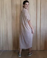 Vestido camisero de denim azul con cuello clásico, cierre frontal con botones y mangas cortas con dobladillo.